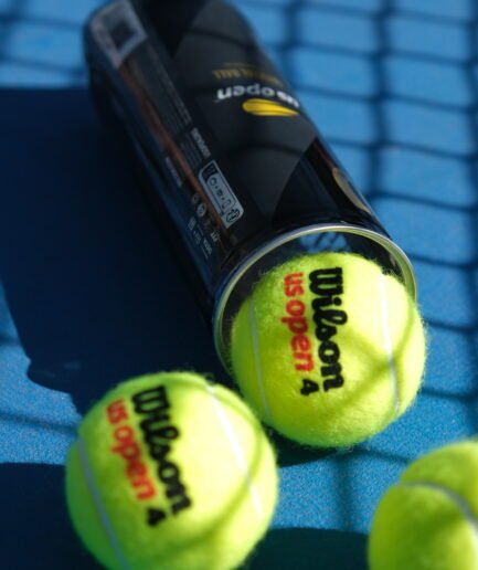 Mavi tenis kortunda Wilson US Open tenis topları ve kutusu