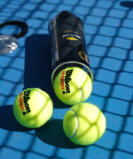 Mavi tenis kortunda Wilson US Open tenis topları ve kutusu